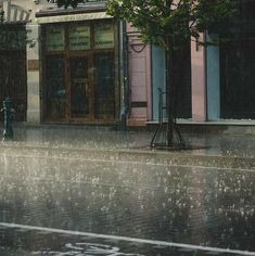 a person walking down the street in the rain with an umbrella over their head while it's raining