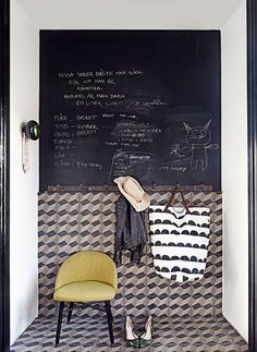 a blackboard with writing on it and a yellow chair in the corner next to it