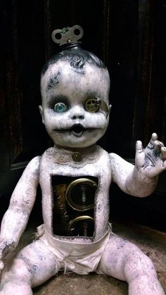 a creepy looking baby doll sitting on the ground with its hands up and eyes wide open