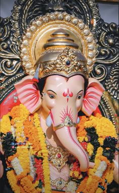 the statue of an elephant is adorned with gold and orange flowers in front of it