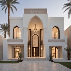 a large white building with palm trees in the front yard and entry way to it