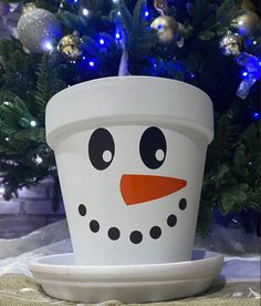 a snowman planter sitting in front of a christmas tree