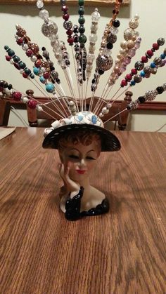 a figurine sitting on top of a wooden table wearing a hat with beads