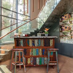 a bar with stools next to it in front of a stair case