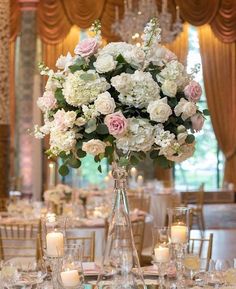 a tall vase filled with lots of white and pink flowers on top of a table