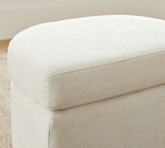 a white ottoman sitting on top of a carpeted floor