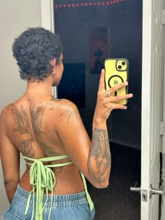 a woman with tattoos taking a selfie in front of a mirror while holding up her cell phone