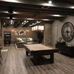 a living room filled with furniture and a pool table in front of a large clock