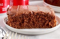 a piece of chocolate cake on a white plate with fork and cups in the background