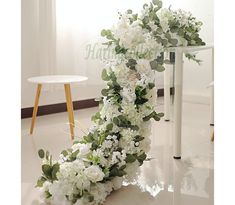 white flowers and greenery are arranged on the floor