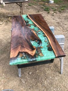 a table made out of wood and glass in the middle of a dirt ground area