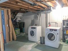 two washers and dryer in a room under construction