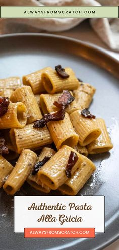 pasta with sun dried tomatoes and bacon on a gray plate next to a white napkin