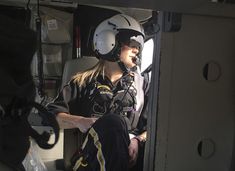 a woman sitting in the cockpit of an airplane wearing a helmet and goggles on her head