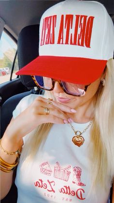 a woman wearing a red and white delta hat sitting in the back seat of a car