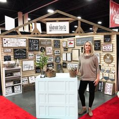 a woman standing in front of a booth with signs on the wall and decorations around it