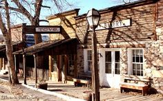 an old western town with stone buildings and wooden benches