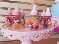 baby bottles filled with gummy bears sitting on top of a pink cake platter