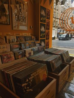 many cds are on display in front of an orange wall and some buildings with posters