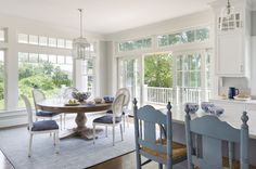 a dining room table and chairs in front of large windows