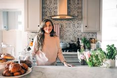 a woman standing in front of a kitchen counter with donuts on the counter top