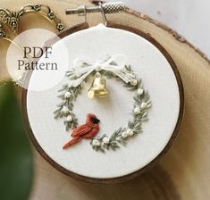 a close up of a embroidery on a piece of cloth with a bird and wreath