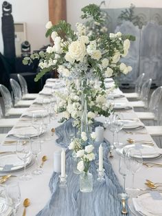 a long table is set with white flowers and place settings