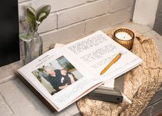 an open book sitting on top of a table next to a candle