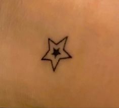 a small star tattoo on the back of a woman's stomach