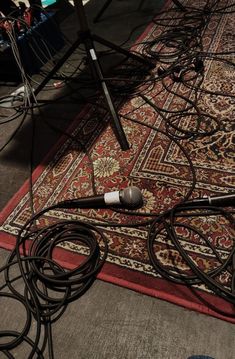 there is a microphone on the floor next to many cords and wires in front of it