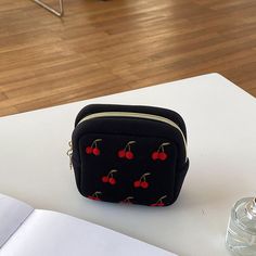 a small black bag with cherries on it sitting on top of a white table