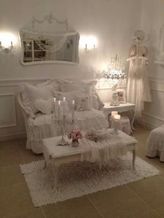 a living room filled with white furniture and lots of candles on top of it's coffee table