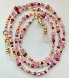 Multiple shades of purple, pink and red with gold and yellow make up this beaded eyeglass chain. Clear rubber and gold eyeglass holders are attached at both ends. Approximately 26 or 31 inches long in total length with the beaded portion being about 23 or 29 inches long. If you would prefer black rubber connectors instead of clear just let me know in the comment section! Also if you are wanting to use this chain for a mask let me know and I will remove the rubber connectors and swap out the lobs Handmade Adjustable Pink Glasses Chains, Adjustable Pink Glasses Chains As Gift, Adjustable Pink Beaded Glasses Chain, Pink Glass Beaded Chain Jewelry, Gold Glasses Chains With Colorful Glass Beads, Bohemian Gold Glasses Chains With Colorful Beads, Pink Glass Jewelry With Beaded Chain, Red Beaded Glasses Chains For Gift, Red Beaded Glasses Chains As Gift