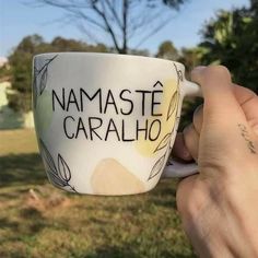 a person holding a coffee cup with the words namaste caralho on it