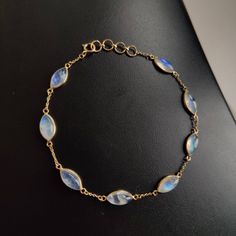 "ITEM DESCRIPTION: >> The bracelet is made from Solid 14K Yellow Gold. Gemstone used is absolutely natural and ethically sourced. >> Natural Rainbow Moonstones cabochons and marquise shape with bezel setting is studded on it with utmost precision. >> This is a minimalist design and is absolutely hassle-free and everyday jewelry. ✓ Gem: Rainbow Moonstone ✓ Gem size & Shape: 5x10 mm (6 pcs) & marquis ✓ Gem weight: 10.17 carats ✓ Bracelet Length: 7\" Inches + 0.5\" Inch Adjustable ✓ Gold purity: 14 Moonstone Gemstone Bracelets, Dainty Round Moonstone Bracelets, Elegant Moonstone Gemstone Bracelets, Gold Bracelet Moonstone, Gold Moonstone Bracelet With Gemstones, Adjustable Moonstone Gemstone Bracelet, Gold Moonstone Gemstone Bracelets, Elegant Moonstone Gemstone Bracelet, Blue Gemstone Moonstone Bracelet