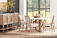 a dining room table with four chairs and a vase on the sideboard in front of it