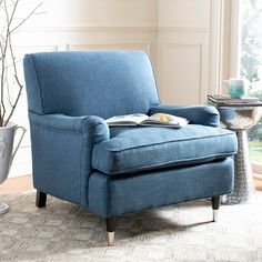 a blue chair sitting on top of a rug next to a vase filled with flowers