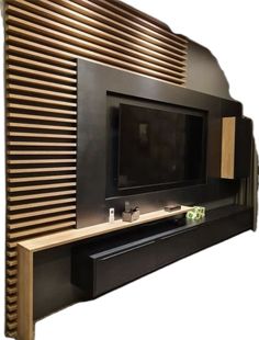 an entertainment center with a flat screen tv mounted on it's side, in front of a wooden slatted wall