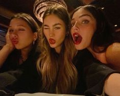 three beautiful young women sitting next to each other in front of a cake with candles on it