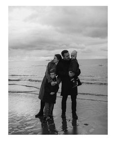 black and white photograph of family on beach with ocean in the background