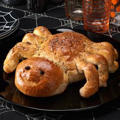 a piece of bread shaped like a crab on a black plate with spider webs