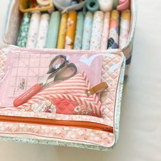 a pair of scissors sitting on top of a pink and white container filled with crayons