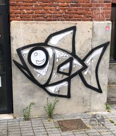 graffiti on the side of a building with a fish drawn on it's face