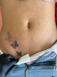 a woman's stomach with butterfly tattoos on her belly and hand in the pocket