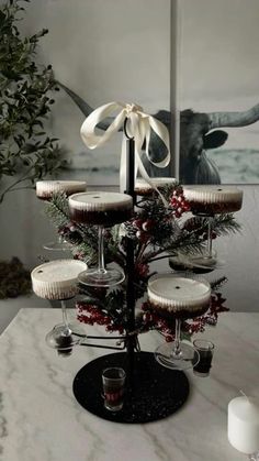 a christmas tree made out of wine glasses on a table with candles and greenery