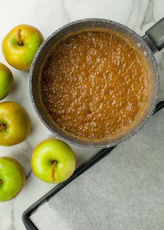 an apple pie with apples around it on a marble counter top next to a spatula