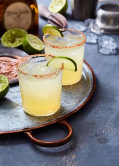 two margaritas on a silver platter with lime slices