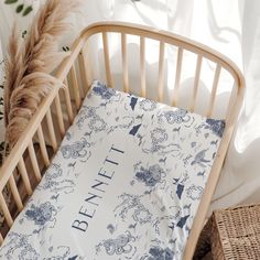 a baby crib with a blue and white bedding next to a brown basket