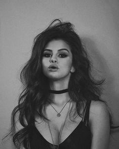 a black and white photo of a woman with long hair wearing choker necklaces