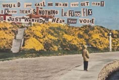 a man standing on the side of a road with lots of signs hanging from it's sides